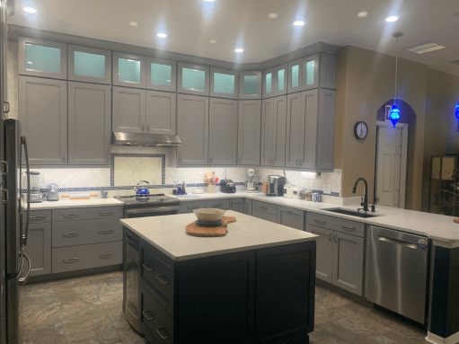 Modern kitchen with gray cabinets, white countertops, central island, and recessed lighting.
