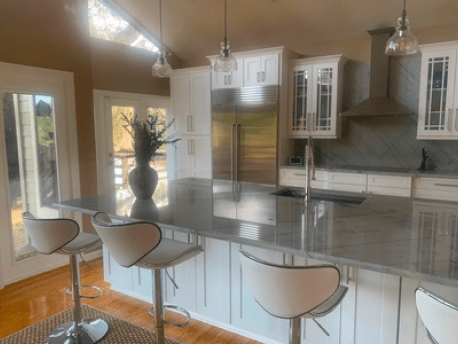 Modern kitchen with marble island, white cabinets, and bar stools in a bright open room