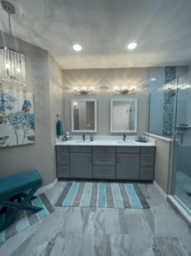 Modern bathroom with double vanity, mirrors, blue accents, striped rug, and decorative wall art