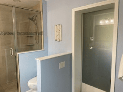 Bathroom with shower stall, toilet, and frosted-glass door in beige and light blue.