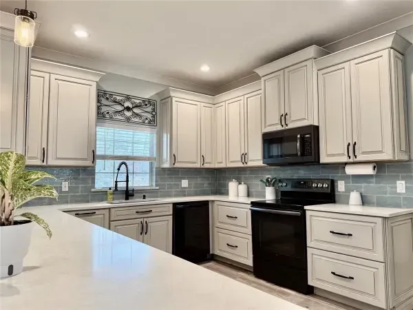 Bright modern kitchen with white cabinets, black appliances, and a large island countertop