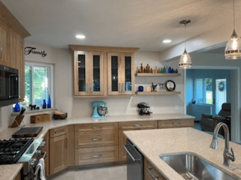 Modern kitchen with wood cabinets, white countertops, pendant lights, and a sink in the foreground