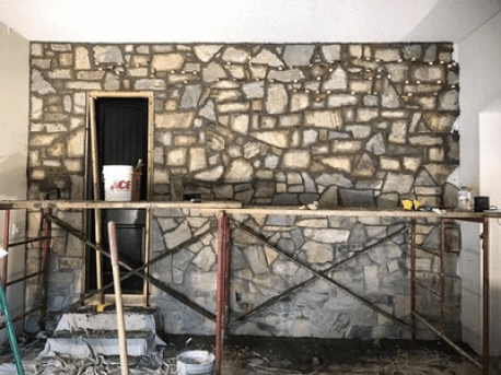 Stone wall under construction with scaffolding and a doorway opening