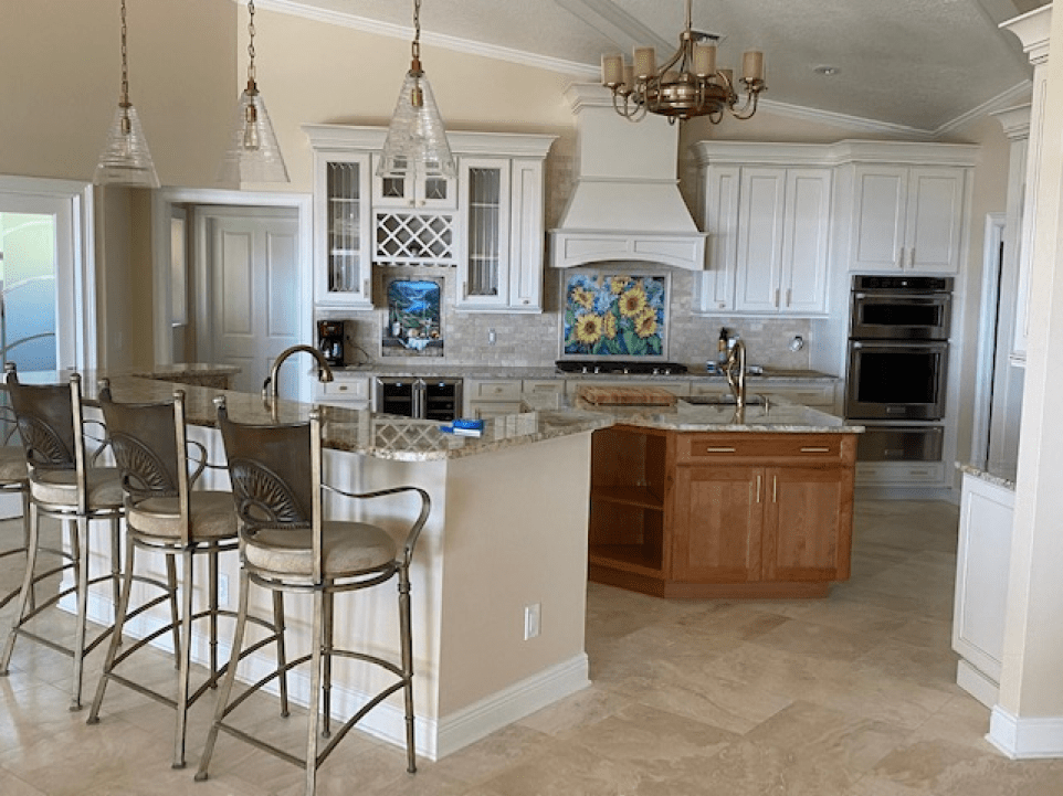 Bright kitchen with white cabinets, granite island, bar stools, and stainless steel appliances