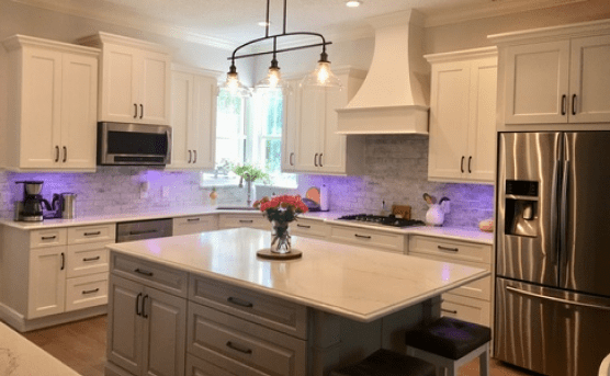 Bright modern kitchen with white cabinets, gray island, stainless steel appliances, and purple under-cabinet lighting