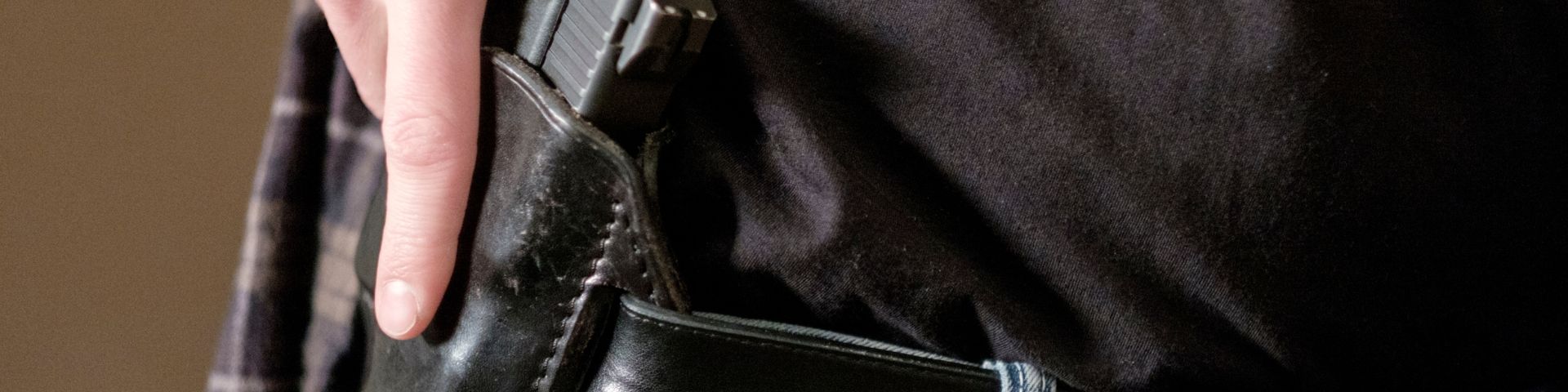 A person is holding a black purse in their pocket.