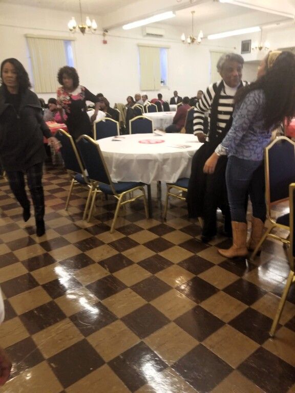 A group of people are standing in a room with tables and chairs