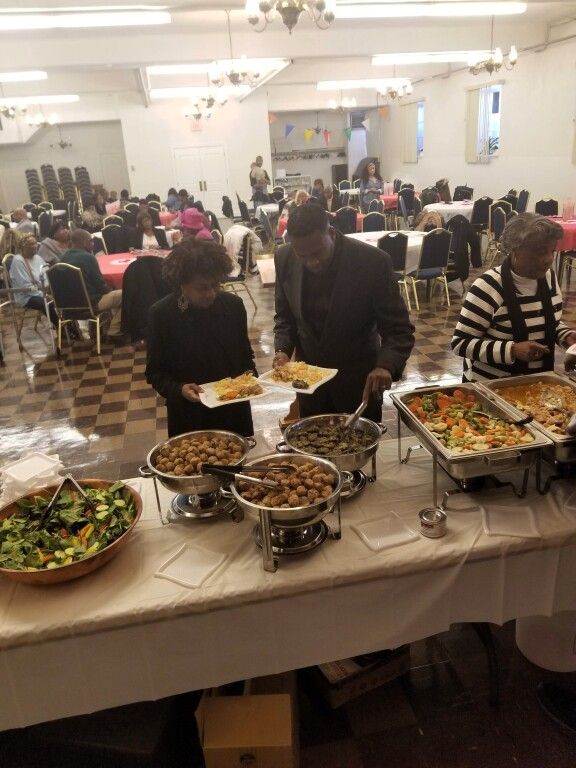 A group of people are standing around a buffet table eating food
