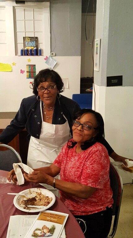 Two women are sitting at a table with plates of food.