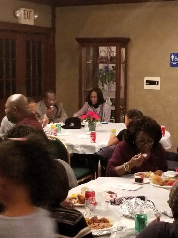 A group of people are sitting at tables in front of an exit sign