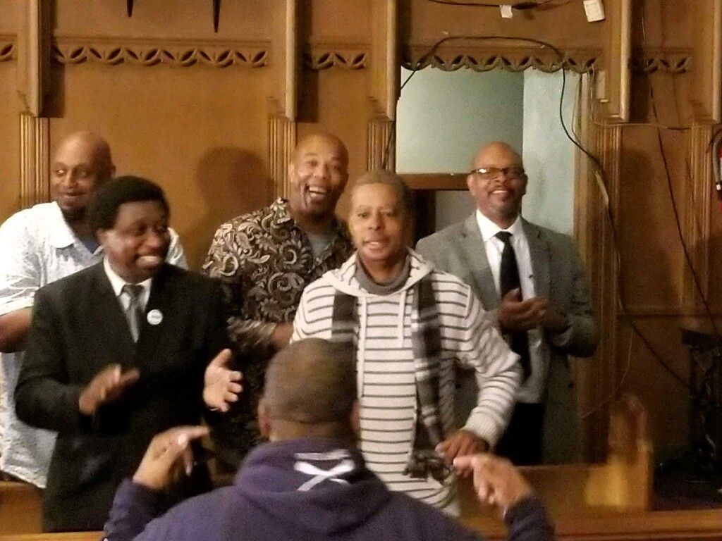 A group of people are standing in a room applauding