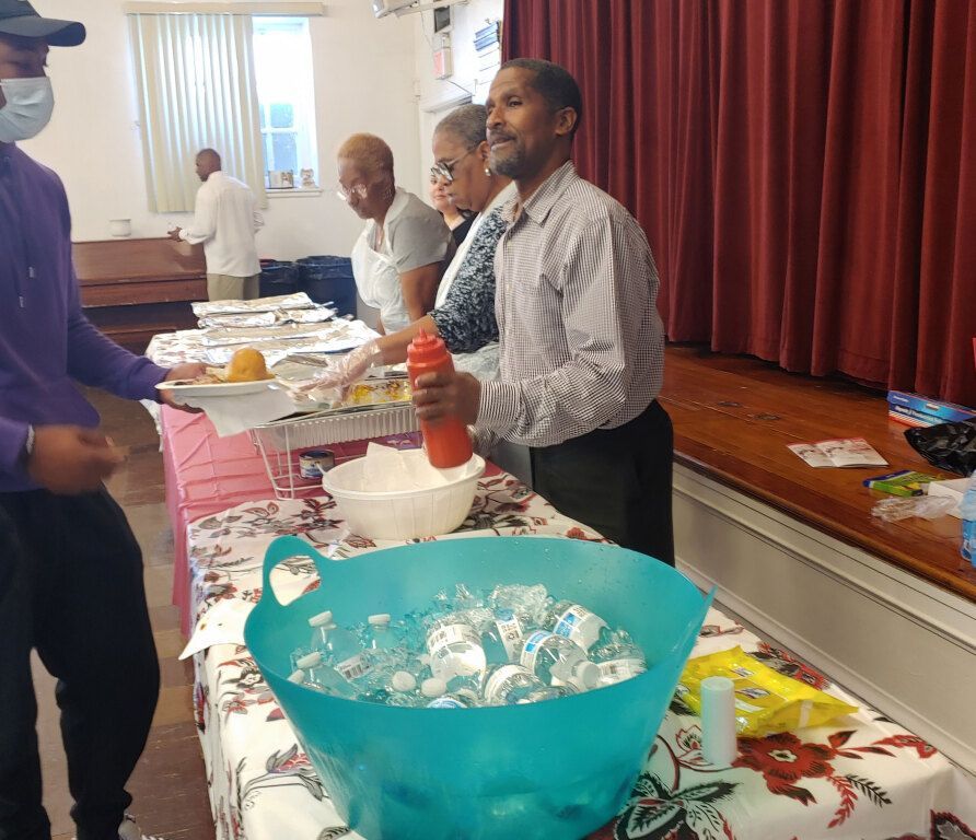 A group of people standing around a table with a blue bucket filled with ice