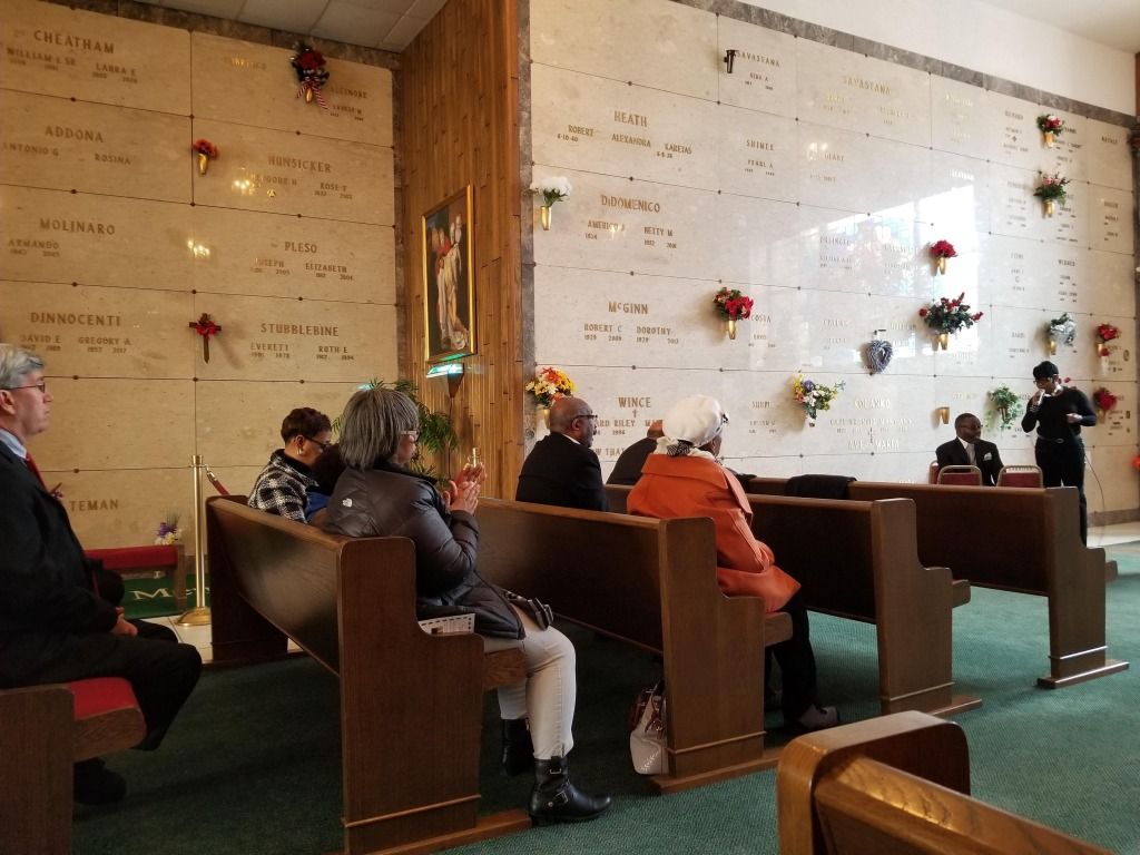 A group of people are sitting on benches in a cemetery