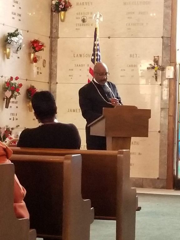 A man stands at a podium in front of a wall that says lawrence