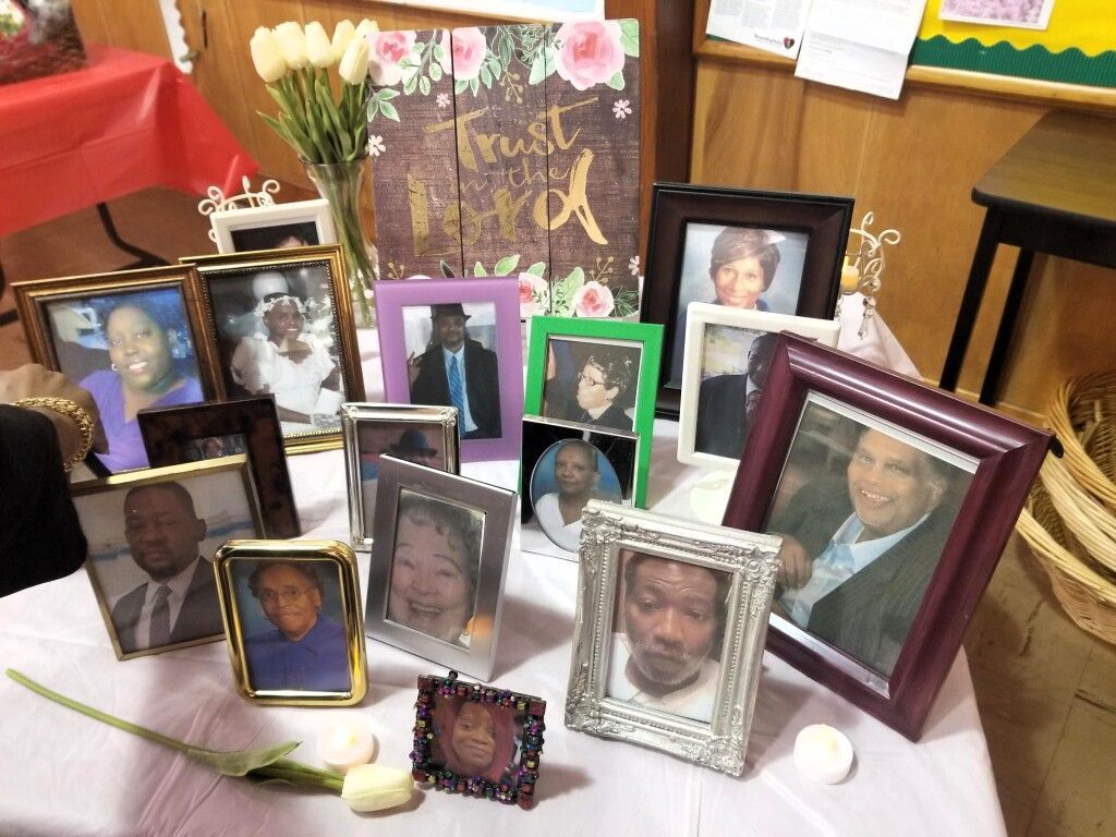 A table topped with lots of framed pictures and flowers.