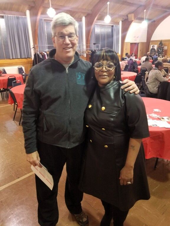 A man and a woman are posing for a picture in a room with red tables