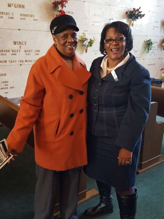 Two women standing in front of a wall that says wince