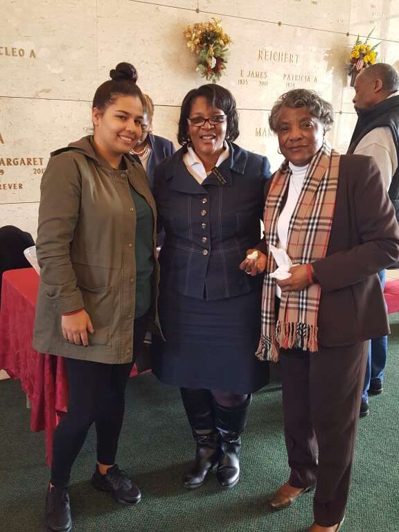 Three women are posing for a picture in front of a grave