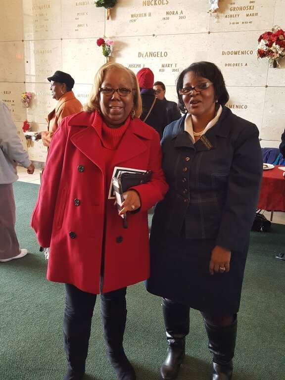 A woman in a red coat stands next to another woman in a blue coat