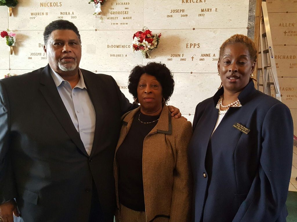 A man and two women pose for a picture in front of a cemetery