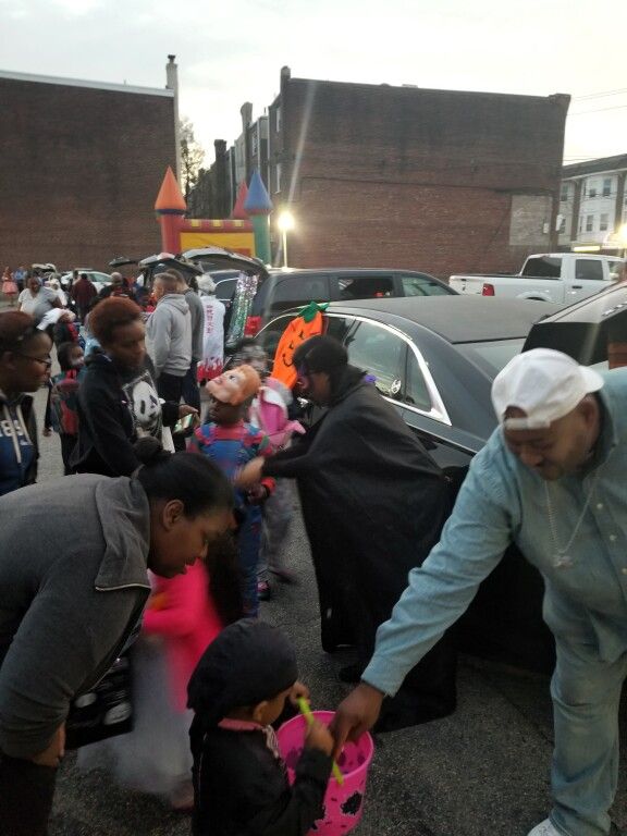 A group of people are standing around a car in a parking lot
