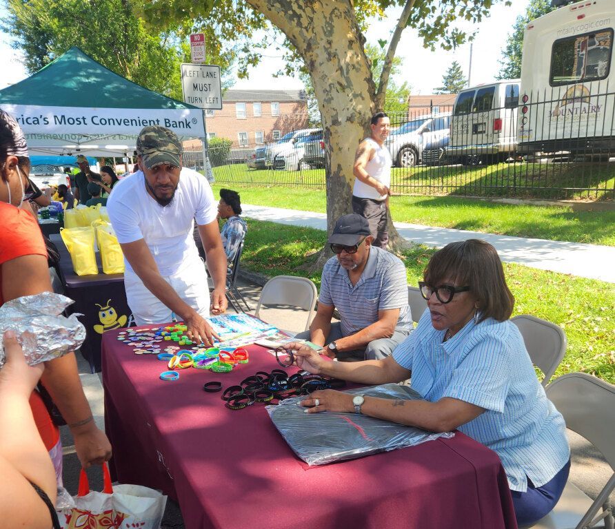 A group of people are gathered around a table in a park