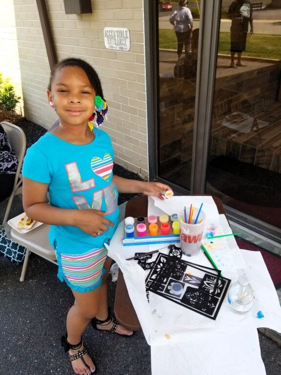 A little girl in a blue shirt with the letter l on it