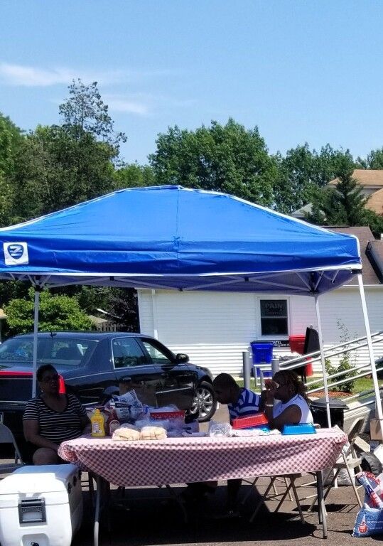 A group of people sitting under a blue tent