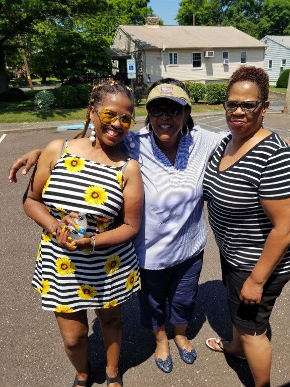 Three women posing for a picture in front of a house
