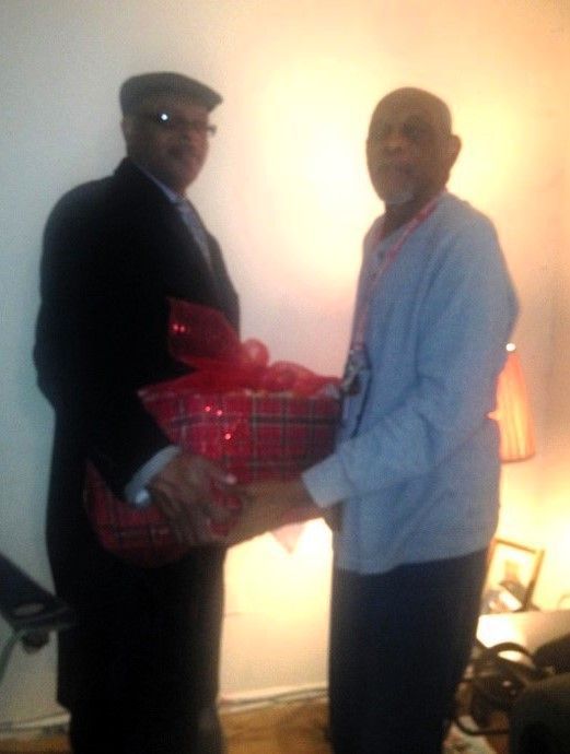 Two men are standing next to each other and one is holding a gift