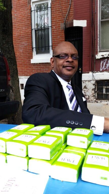 A man in a suit and tie is sitting at a table with boxes of mail on it