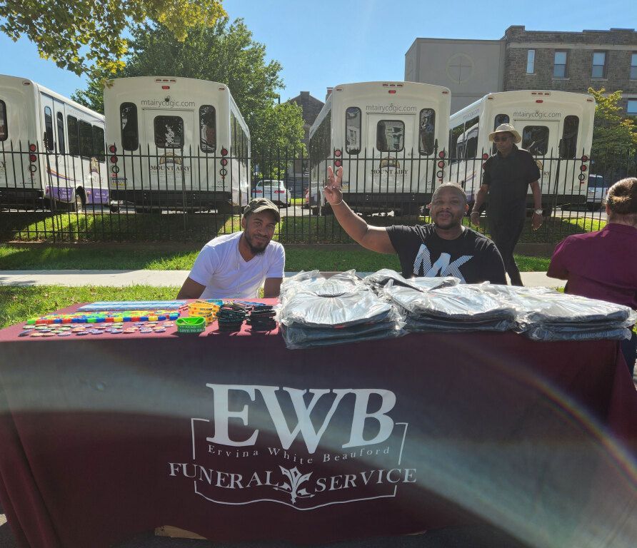 A man stands in front of a table that says ewb funeral service