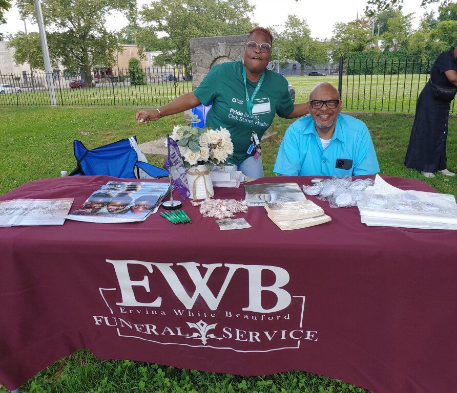 Two people standing behind a table that says ewb funeral service