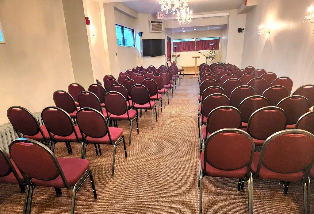 Rows of red chairs are lined up in a large room.