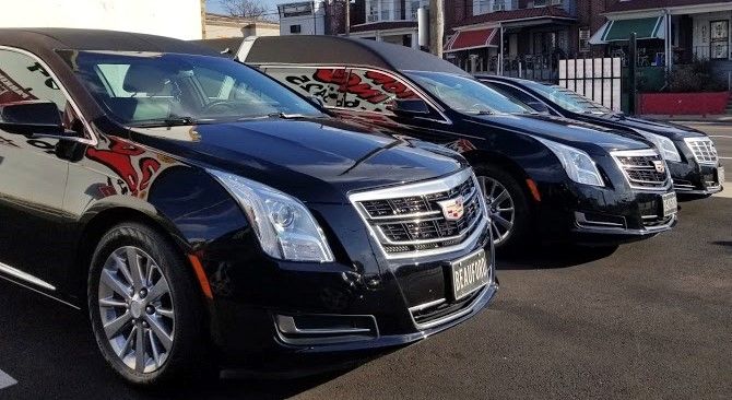 A row of black cadillacs are parked in a parking lot.
