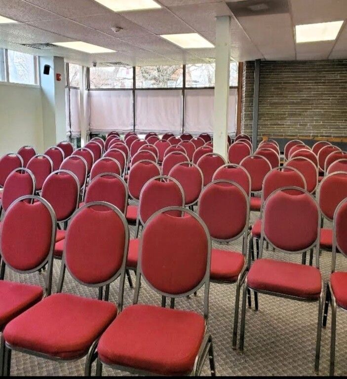 Rows of red chairs are lined up in a room