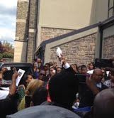 A group of people are standing in front of a building holding up papers.