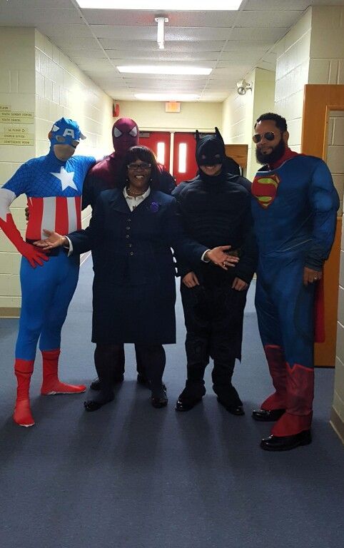 A group of people in superhero costumes are posing for a picture in a hallway.