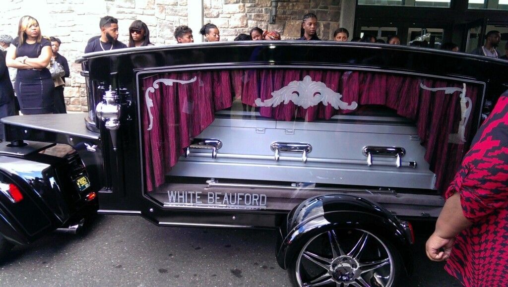 A black coffin is being pulled by a motorcycle