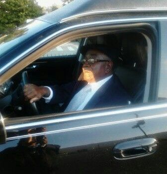 A man in a suit and tie is driving a black car.