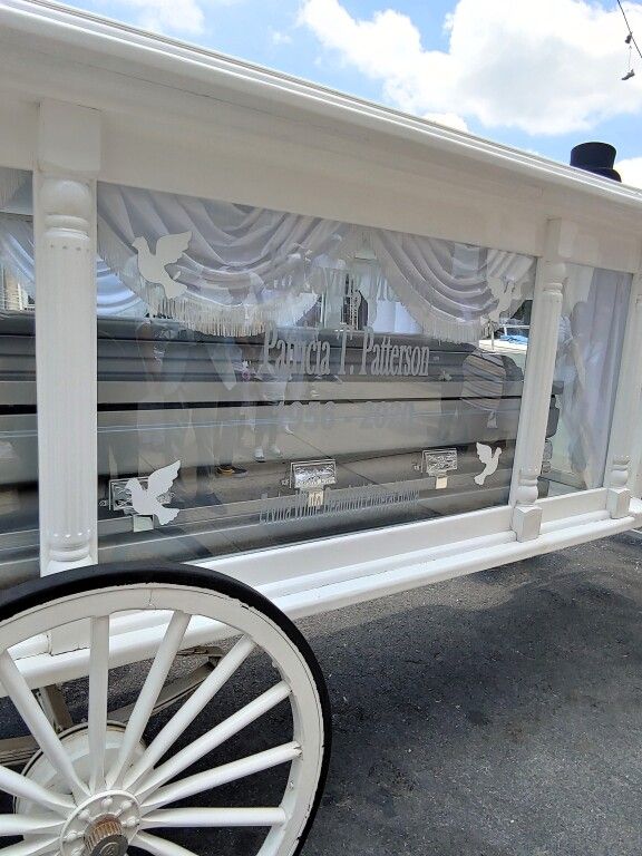 A white horse drawn carriage with a coffin in it