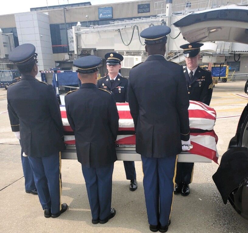 A group of soldiers carrying a coffin with an american flag on it