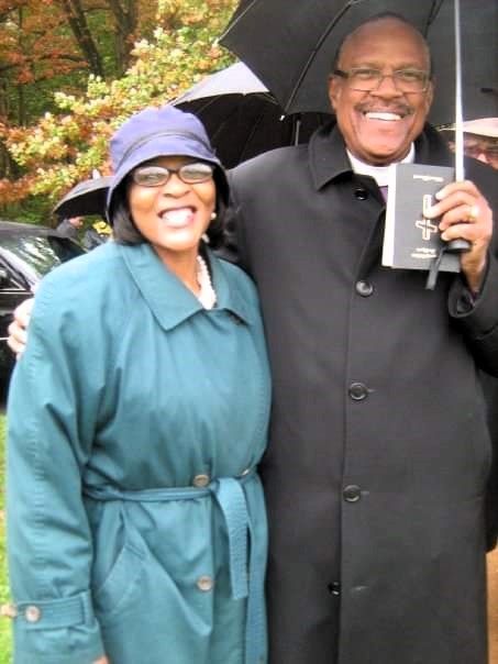 A man and a woman are posing for a picture in the rain