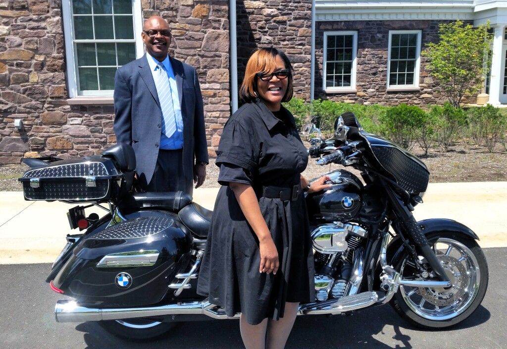 A man and woman standing next to a black motorcycle