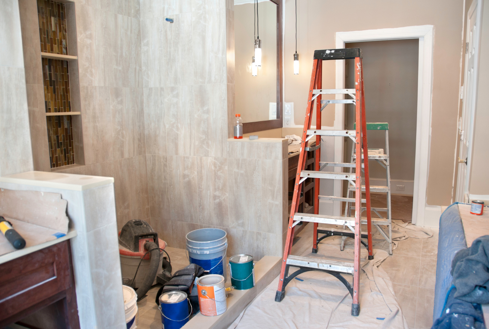 A bathroom under construction with buckets of paint and a ladder.