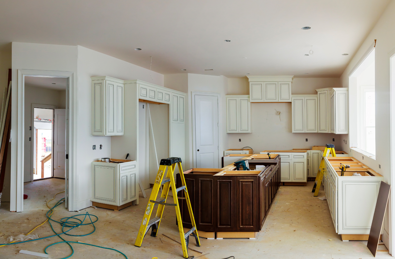 A kitchen under construction with a yellow ladder in the middle of the room.