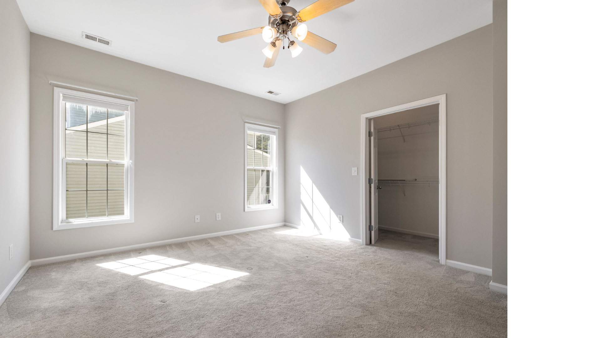 An empty bedroom with a ceiling fan and a walk in closet.
