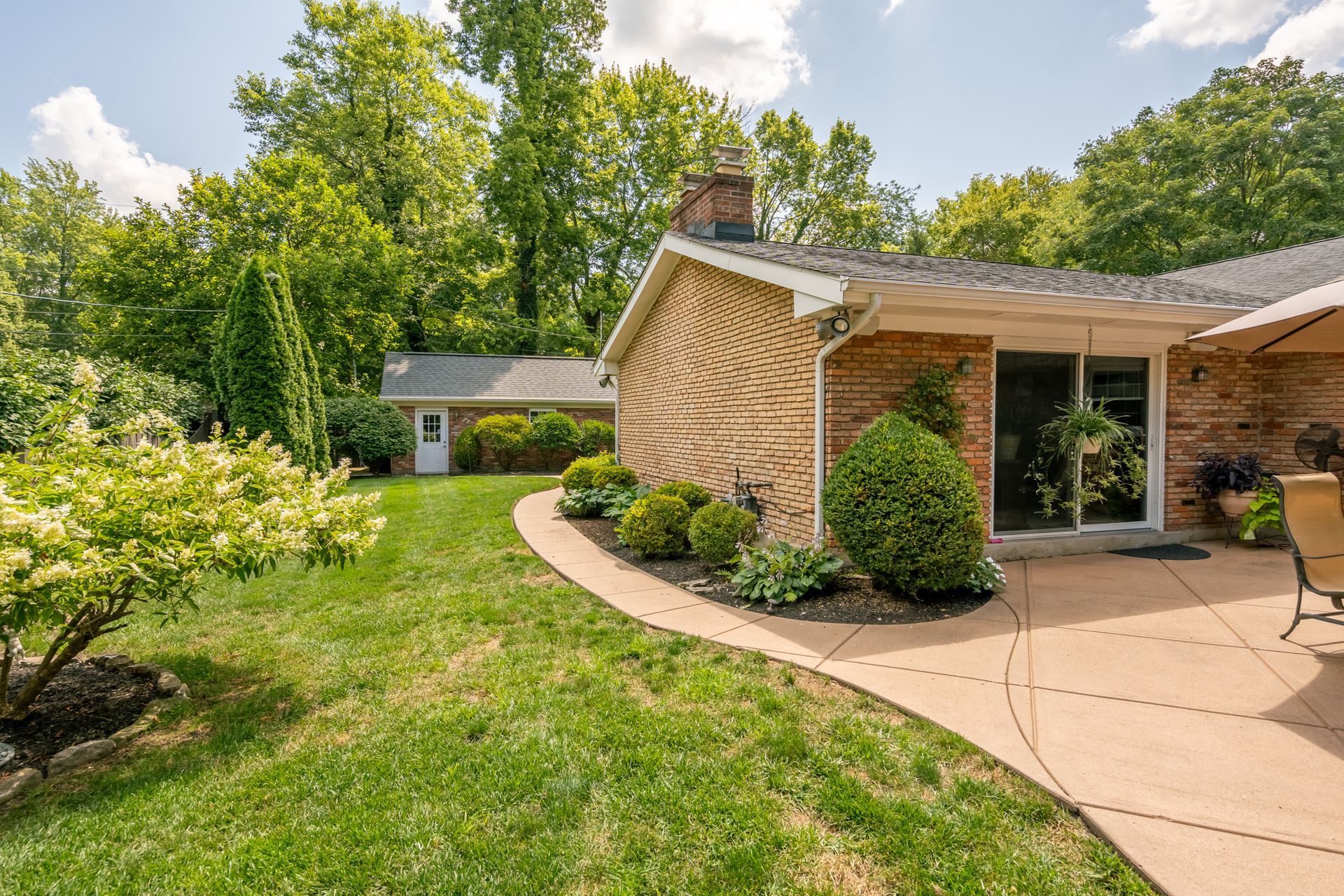 Exterior of a brick house with a patio and lush green yard.
