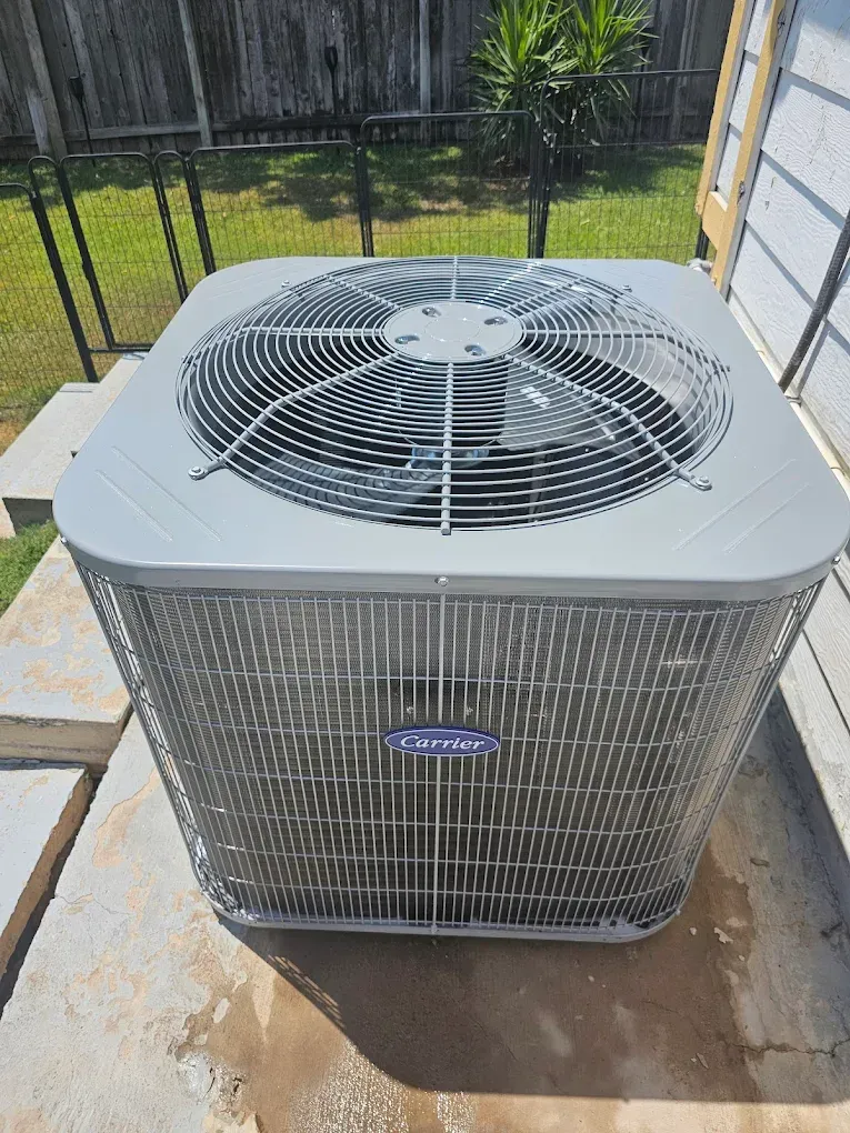 A Carrier air conditioning unit on a concrete pad with a grass background.