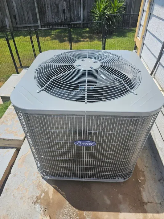 A Carrier air conditioning unit sits outside on a concrete slab.